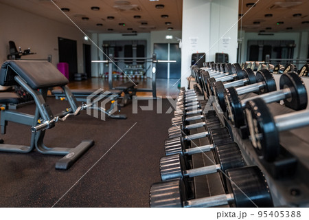 Modern light gym. Sports equipment in gym. Barbells of different weight on rack. 95405388