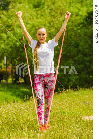 Girl doing exercises outdoor, using resistance fit band. Girl doing exercises outdoor, using resistance fit band. 95408549