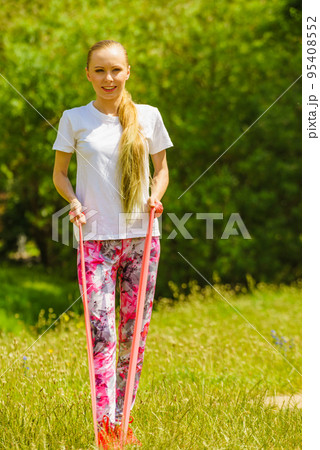 Girl doing exercises outdoor, using resistance fit band. 95408552