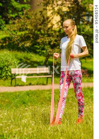 Girl doing exercises outdoor, using resistance fit band. 95408554