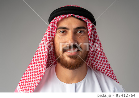 Portrait of smiling young Arab man on gray background Portrait of smiling young Arab man on gray background 95412764
