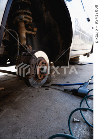 Car service and repair. Tire service. Repair of a broken wheel. Balancing. View of the car on the dock with the wheel removed. Car service and repair. Tire service. Repair of a broken wheel. Balancing. View of the car on the dock with the wheel removed. 95413009