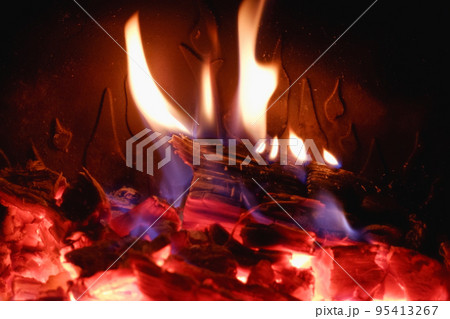 Fire in the fireplace with glass close-up. Firewood is burning in the fireplace. 95413267