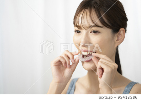 両手でマウスピースを持つ女性 95413586