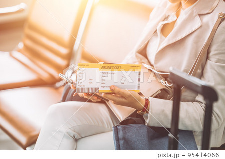 traveller sitting in waiting area with boarding pass ticket self check in using smartphone application traveller sitting in waiting area with boarding pass ticket self check in using smartphone application 95414066