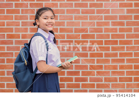 Thai asian school girl teen happy smile in uniform handle book and school bag with copy space 95414104