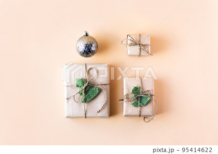 Christmas composition of a gift box in gray craft paper decorated with a knitted green Christmas tree and a Christmas ball on a orange background, the concept of New year and Christmas, top view Christmas composition of a gift box in gray craft paper decorated with a knitted green Christmas tree and a Christmas ball on a orange background, the concept of New year and Christmas, top view 95414622