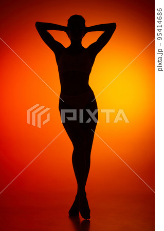 Silhouette of female full-length body isolated over orange background. Relaxation, wellness Silhouette of female full-length body isolated over orange background. Relaxation, wellness 95414686