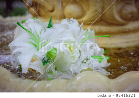 The Wedding Bridal Bouquet Of White Roses Lies In An Old Fountain Under Splashes And Drops Of Water. The Wedding Bridal Bouquet Of White Roses Lies In An Old Fountain Under Splashes And Drops Of Water. 95416321