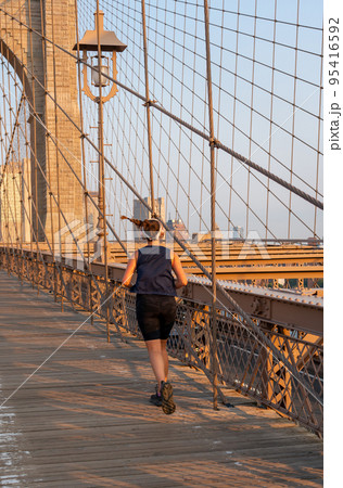 A young girl in a black uniform jogging on the Brooklyn Bridge A young girl in a black uniform jogging on the Brooklyn Bridge 95416592