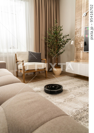 Homework of a round black vacuum cleaner robot in a modern apartment 95416702