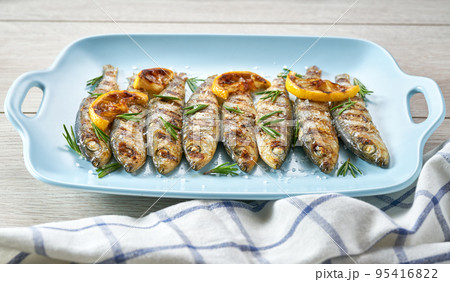 Grilled sardines with salt, herbs and lemon slices on a white table, selective focus. Grilled sardines with salt, herbs and lemon slices on a white table, selective focus. 95416822