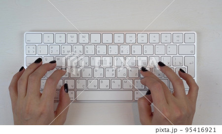 A young girl is typing on a wireless keyboard. Girl's hands close up. View from above. A young girl is typing on a wireless keyboard. Girl's hands close up. View from above. 95416921