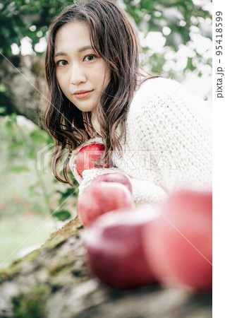 赤いりんごを持った白いニットを着た女性のポートレート 95418599