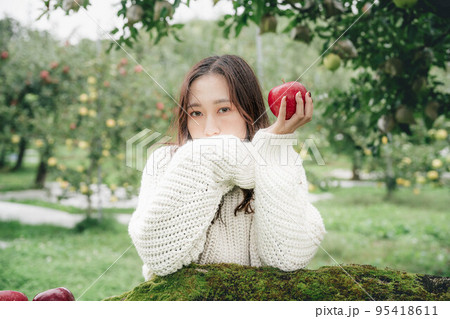 赤いりんごを持った白いニットを着た女性のポートレート 赤いりんごを持った白いニットを着た女性のポートレート 95418611