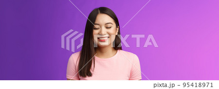 Cheerful tender lovely asian girl brunette, close eyes happily smiling, satisfied, receive good news, dream come true, stand purple background joyful, grinning from happiness and joy 95418971