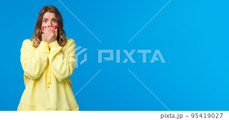 Shocked speechless and concerned young woman seeing bad accident, terrifying scene in movie, cover mouth with hands not to scream, stare with frightened eyes camera Shocked speechless and concerned young woman seeing bad accident, terrifying scene in movie, cover mouth with hands not to scream, stare with frightened eyes camera 95419027