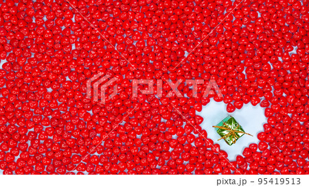 Christmas holidays concept with space for text small green gift in heart shape against red color peppermint heart shaped candies background. New Year, Birthday gift, Valentines day, Love 95419513