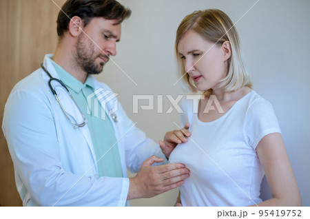 Doctor palpating the painful mammary gland of a woman 95419752
