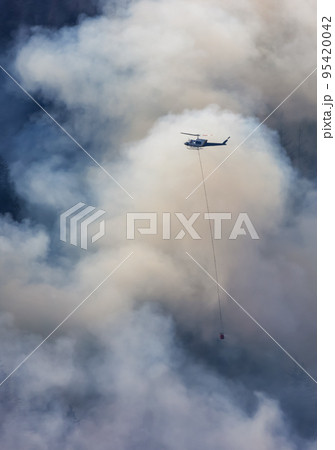Wildfire Service Helicopter flying over BC Forest Fire and Smoke on the mountain near Hope 95420042