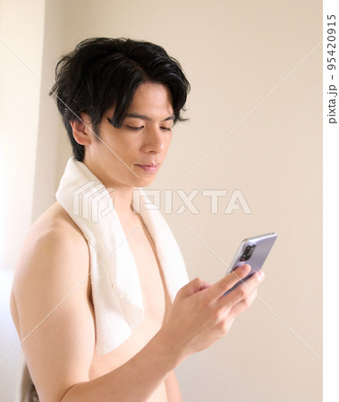 洗面所でスマホを使う若い男性　メンズビューティー　イメージ 95420915