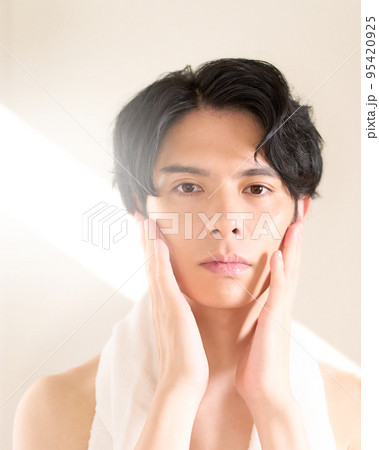 鏡を見ながら頬を触る若い男性 スキンケア メンズビューティー イメージの写真素材