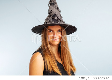 Happy brunette woman in halloween witch costume with black hat 95422512
