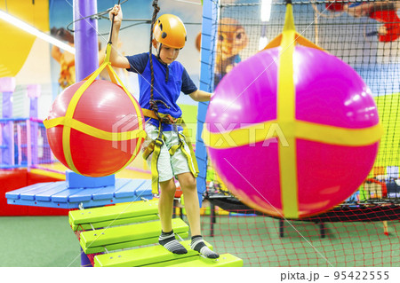 Boy in protective gear holding safety rope and passing obstacle course 95422555