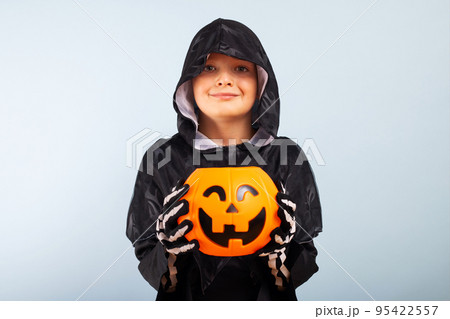 Cute little boy in a costume with a pumpkin basket jack-o-lantern 95422557