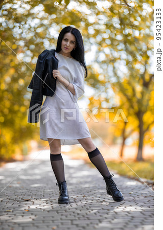 Young brunette girl posing in the park against golden autumn Young brunette girl posing in the park against golden autumn 95423133