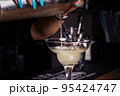 Girl bartender pours cocktail into glass. Close-up. 95424747