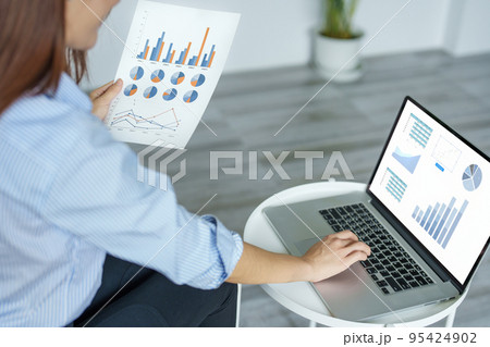 self employed, business owner, pleasure from work, Asian woman using computer holding financial documents to check or plan budget, manage investment risk at home. 95424902