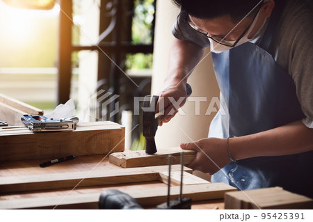 Entrepreneur Woodwork holding hammer to assemble the wood pieces as the customer ordered. Entrepreneur Woodwork holding hammer to assemble the wood pieces as the customer ordered. 95425391