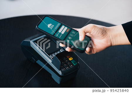 Secure payment technology concept and service charge, customers are using their phone to pay using paywave technology by tapping near the electronic card terminal 95425840