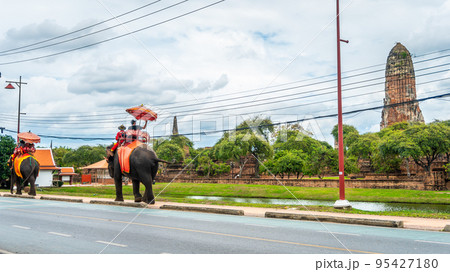 Tourists wear a mask to sit on the back of an elephant to visit Rama Temple in the Ayutthaya Historical Park. during the covid 19 epidemic live a new normal life 95427180