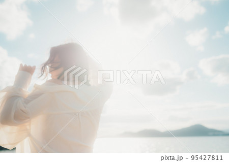 海辺で風に吹かれる女性の後ろ姿|自然光と余白のある構図 海辺で風に吹かれる女性の後ろ姿|自然光と余白のある構図 95427811