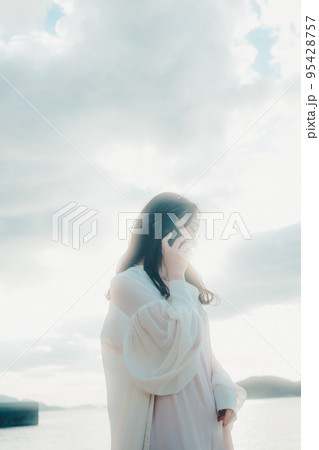 海辺で電話をかける女性の写真 海辺で電話をかける女性の写真 95428757