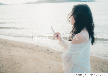海辺で電話をかける女性の写真 95428759