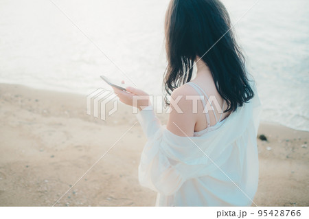 海辺で電話をかける女性の写真 海辺で電話をかける女性の写真 95428766