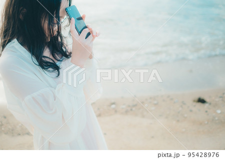 海辺で電話をかける女性の写真 海辺で電話をかける女性の写真 95428976