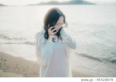 海辺で電話をかける女性の写真 海辺で電話をかける女性の写真 95428979