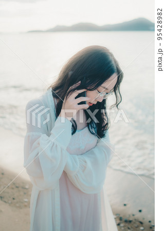 海辺で電話をかける女性の写真 海辺で電話をかける女性の写真 95428982