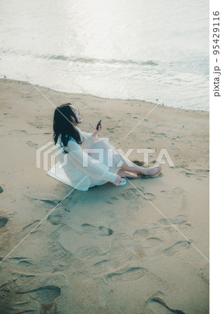 海辺で電話をかける女性の写真 海辺で電話をかける女性の写真 95429116