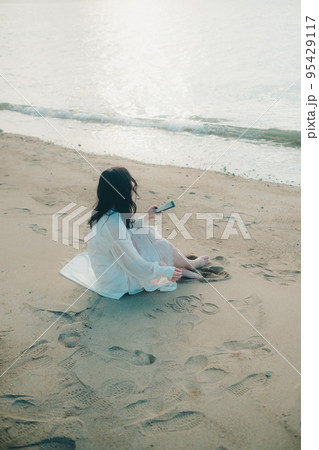 海辺で電話をかける女性の写真 95429117
