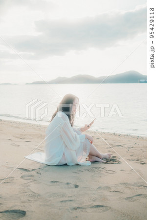 海辺で電話をかける女性の写真 95429118