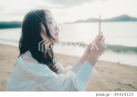 海辺で電話をかける女性の写真 海辺で電話をかける女性の写真 95429125