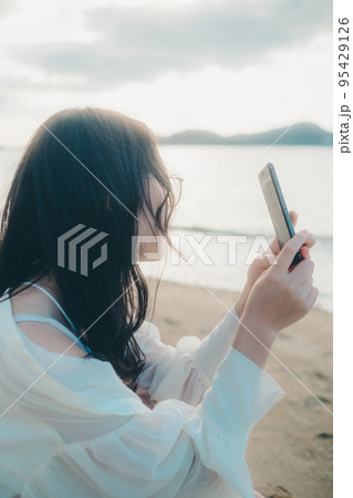 海辺で電話をかける女性の写真 95429126