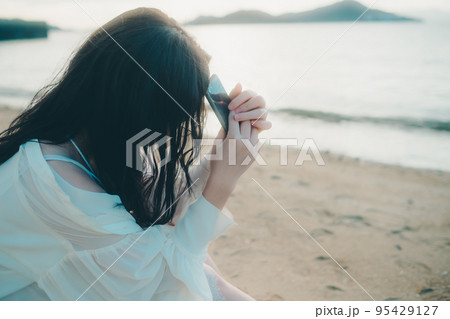 海辺で電話をかける女性の写真 95429127