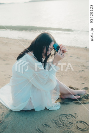 海辺で電話をかける女性の写真 95429128