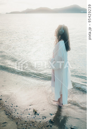 海辺で音楽を聴く女性の写真 95429239